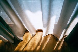 Sunlight streaming through white curtains, casting soft shadows, evoking calm reflection, and quiet inner space.