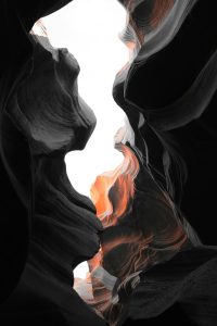 Abstract image of grey and black shapes colliding with hints of red, representing the tension, alertness, and constricted feelings associated with hypervigilance.