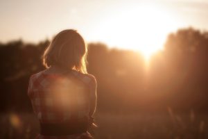 Woman looking towards a golden sunset, representing hope and moving forward after IVF and fertility struggles.