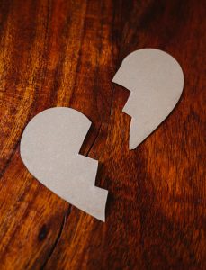 Wooden heart split apart, cracked and splintered, representing the ache of grief with no ritual to mark it.